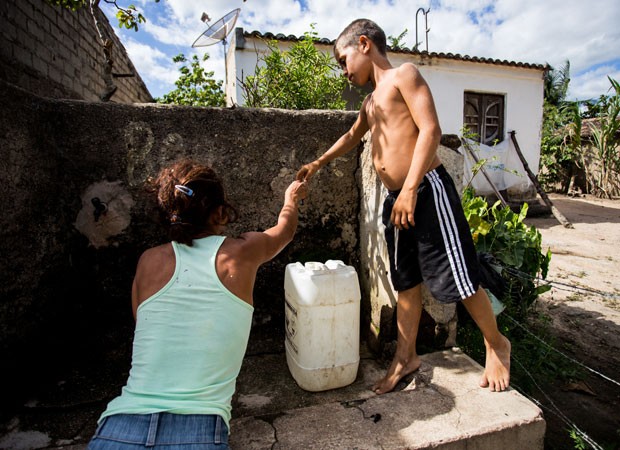 A dona de casa Creuza Gomes da Silva, de 37 anos, tenta buscar água no ‘chafariz’, uma torneira dividida por todos os vizinhos. Desta vez, ela voltou de mãos vazias na companhia do filho (Foto: Jonathan Lins/G1 AL)